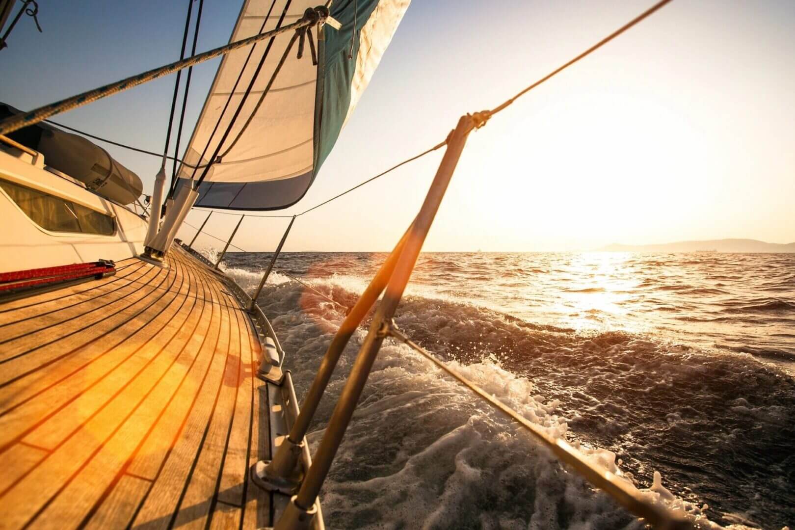 Sailboat cruising at sunset with sails catching the breeze.