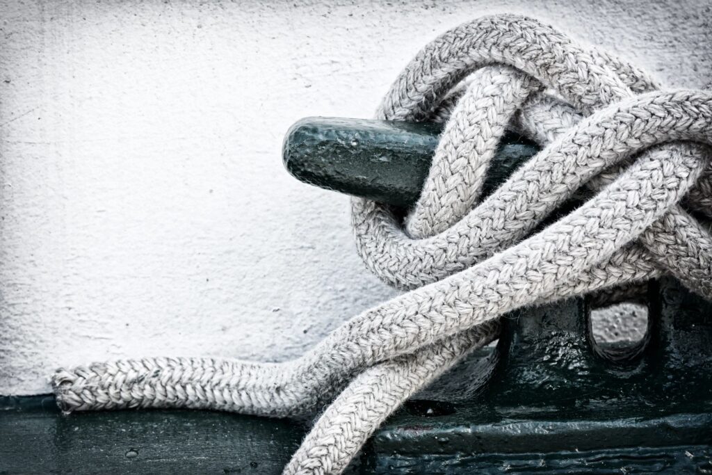 Close-up of a rope tied around a cleat on a boat.