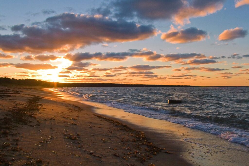 Sunset over a sandy beach with waves.