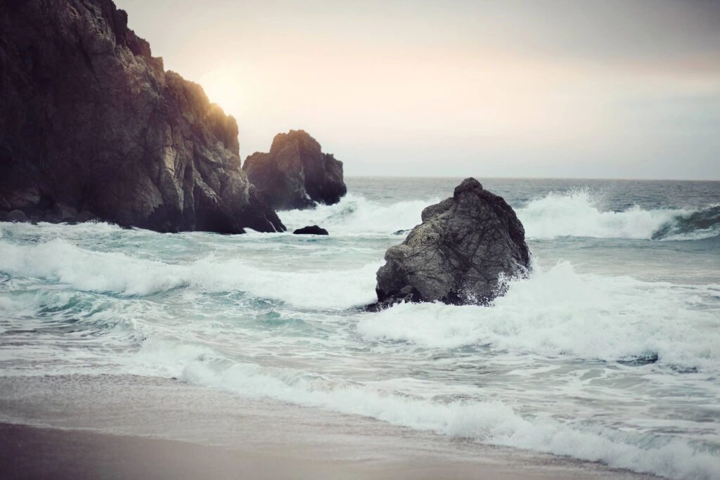 Rocky beach with waves and sunset.